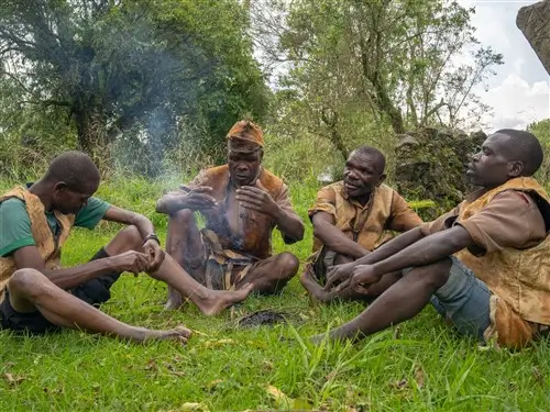 A group of Batwa tribe members conversing in the grass in Uganda.