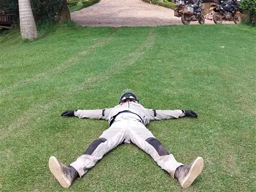 Exhausted rider on moto safari resting on the grass in Uganda.